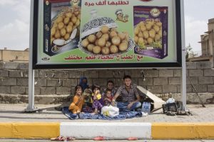 A Sunni refugee family from Mosul takes shelter underneath an ad for sweets. They had to leave all of their possessions behind when they fled to escape bombings by the Iraqi Air Force. Photo by: Hawre Khalid